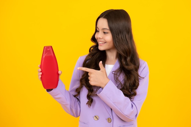 Uma Adolescente Feliz Com Cabelo Longo Sorri Enquanto Segura Uma Garrafa De Shampoo, Cercada Por Vários Shampoos, Condicionadores E Géis De Banho, Exibindo Seus Produtos Para Cuidados Com Os Cabelos.