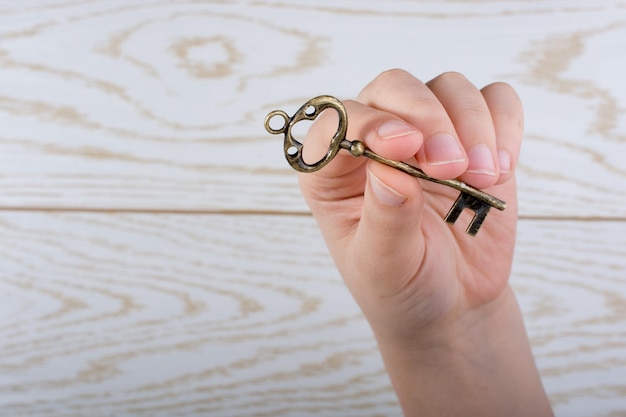 Uma Vista Cortada De Uma Mão Segurando Uma Chave Acima De Uma Mesa De Madeira.