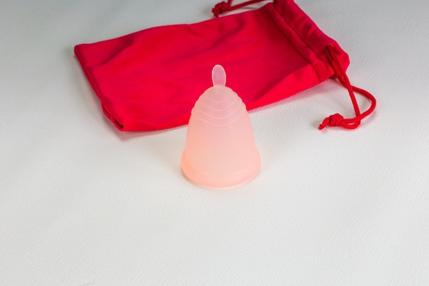 Uma Copa Menstrual Colocada Contra Uma Parede Branca, Destacando Seu Design Ecológico Como Uma Alternativa Aos Produtos Tradicionais Para O Período, Com Amplo Espaço Para Texto.
