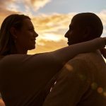 Silhueta De Um Casal Interracial Amoroso Se Encarando Na Praia Durante O Pôr Do Sol, Compartilhando Um Momento Romântico Contra Um Céu Dourado.