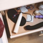Uma Mesa De Cabeceira Com Uma Gaveta Cheia De Vários Produtos Para Adultos E Brinquedos Sexuais, Situada Em Um Ambiente Seguro E Acolhedor.