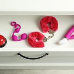 Uma Gaveta De Madeira Aberta Exibindo Uma Variedade De Brinquedos Sexuais Modernos Organizados De Maneira Ordenada, Destacando Diferentes Formas E Cores.