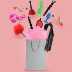 Uma Exibição Vibrante De Vários Brinquedos Sexuais E Acessórios Saindo De Uma Sacola De Papel Em Um Fundo Rosa.