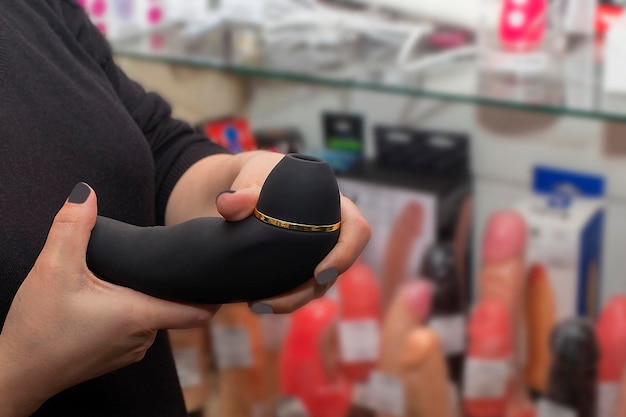 Um Funcionário De Sex Shop Exibindo Uma Variedade De Brinquedos Sexuais Em Exibição, Enfatizando A Segurança Do Consumidor Em Um Ambiente De Varejo.